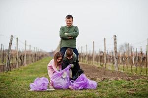 Family with trash bag collecting garbage while cleaning in the vineyards . Environmental conservation and ecology, recycling. photo