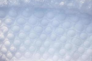 A trace of convex circles in the snow, a circle tread print on a white background. Imprint pattern of circles in fresh white snow, top view. photo