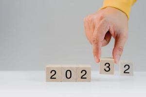 Hand holding a wooden cube with numbers 2023 on white background. Goal in the new year 2023. Business development strategy, advancement and goal concept photo