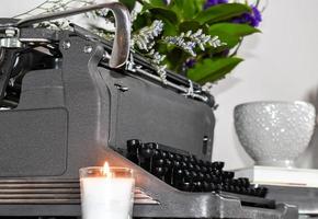 máquina de escribir antigua con velas y flores foto