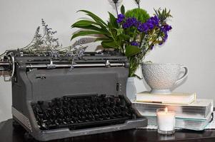 Vintage Typewriter With Purple Flowers, A Candle, A Stack Of Books, And Tea Cup photo