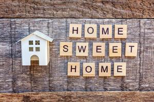Miniature toy model house with inscription HOME SWEET HOME letters word on wooden background photo