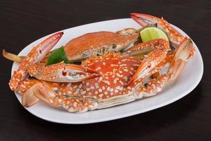 Boiled crabs on the plate and wooden background photo