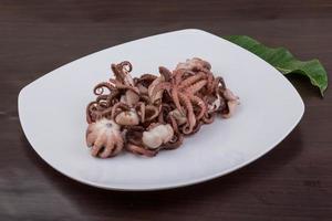 Boiled octopus on the plate and wooden background photo