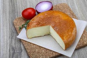 Suluguni cheese on wooden board and wooden background photo