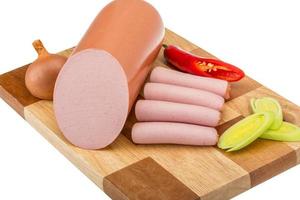 Sausages on wooden board and white background photo