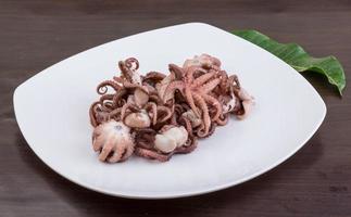 Boiled octopus on the plate and wooden background photo