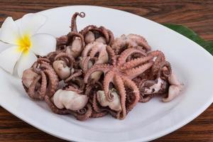 Boiled octopus on the plate and wooden background photo