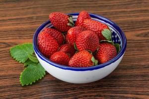 Fresh strawberry in a bowl on wooden background photo