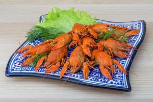 Boiled crayfish on the plate and wooden background photo