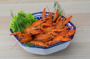 Boiled crayfish in a bowl on wooden background photo