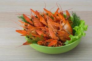 Boiled crayfish in a bowl on wooden background photo