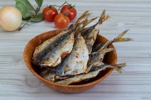 Dry fish in a bowl on wooden background photo