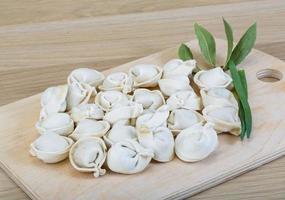 Raw dumplings on wooden board and wooden background photo