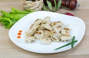 Roasted pierogi on the plate and wooden background photo