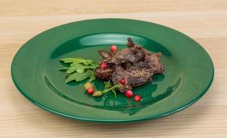 Roasted venison on the plate and wooden background photo