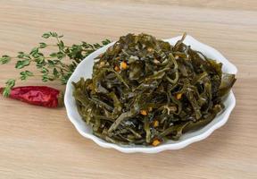 Laminaria salad in a bowl on wooden background photo