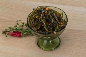 Laminaria salad in a bowl on wooden background photo