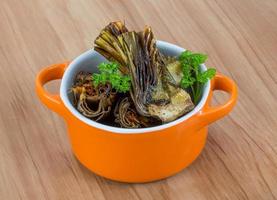 Grilled artishokes in a bowl on wooden background photo