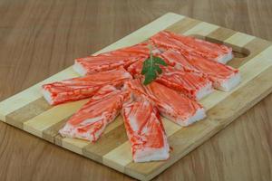 Crab sticks on wooden board and wooden background