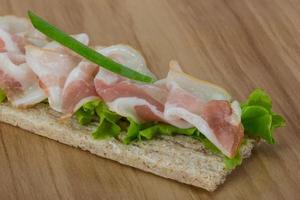 Bacon sandwich on wooden board and wooden background photo