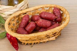 Mini salami in a basket on wooden background photo