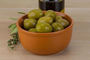 Green olives in a bowl on wooden background photo