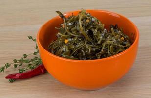 Laminaria salad in a bowl on wooden background photo