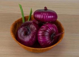 cebolla violeta en un bol sobre fondo de madera foto