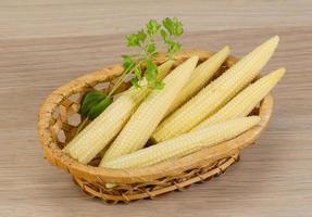 Baby corn in a basket on wooden background photo