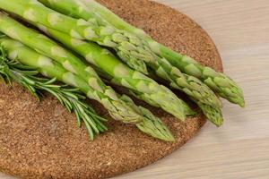 Raw asparagus on wooden board and wooden background photo