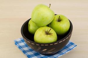 Green apple in a bowl on wooden background photo