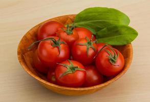 Cherry tomatoes in a bowl on wooden background photo