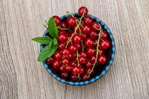 Red currants in a bowl on wooden background photo