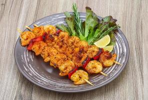 Prawn skewer on the plate and wooden background photo