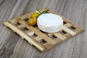 Brie cheese on wooden board and wooden background photo