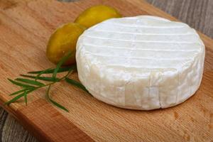 queso brie sobre tablero de madera y fondo de madera foto