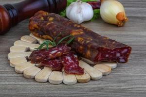 Salami sausage on wooden board and wooden background photo