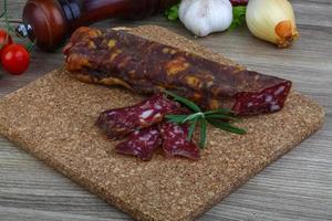 Salami sausage on wooden board and wooden background photo