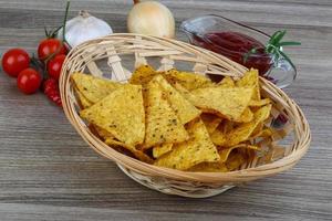 Nachos in a basket on wooden background photo