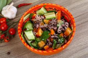 Octopus salad in a bowl on wooden background photo