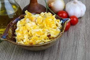 Scrambled eggs in a bowl on wooden background photo