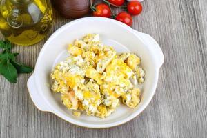 Scrambled eggs in a bowl on wooden background photo