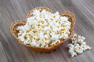 palomitas de maíz en una cesta sobre fondo de madera foto