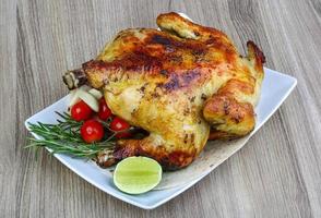 pollo a la parrilla en el plato y fondo de madera foto