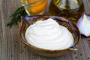 Mayonnaise sauce in a bowl on wooden background photo