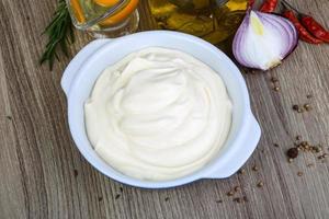 Mayonnaise sauce in a bowl on wooden background photo