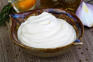 Mayonnaise sauce in a bowl on wooden background photo