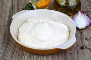 Mayonnaise sauce in a bowl on wooden background photo