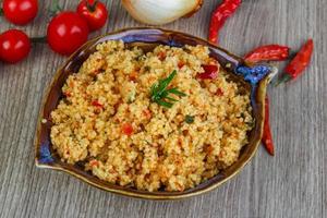 Couscous in a bowl on wooden background photo